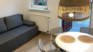 Uma sala de estar acolhedora com um sofá cinza, uma mesa redonda com dois jogos americanos de fibra natural e uma luminária pendente de vime.