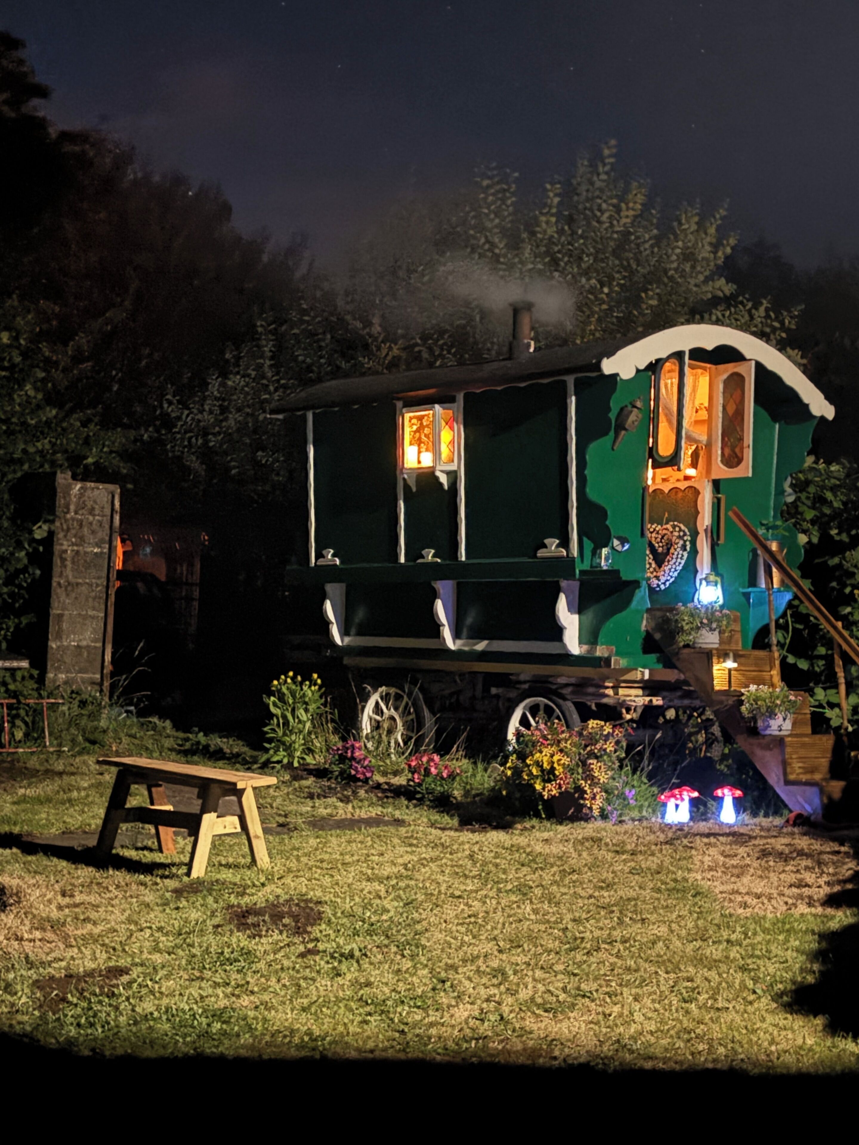 A green train-themed structure with a small porch and a bench in front.