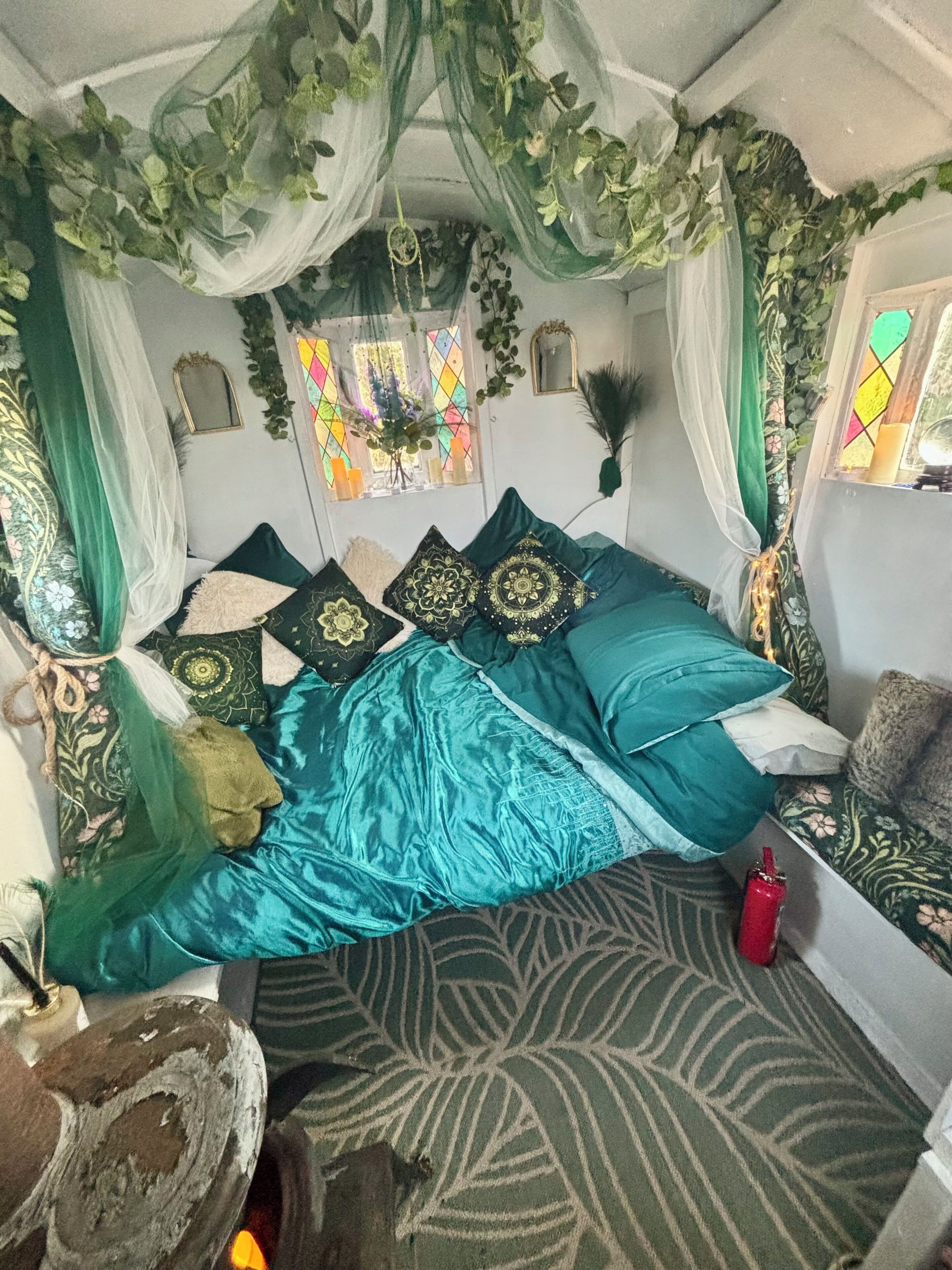Una habitación con una cama, una mesita y un ventanal con cortinas.