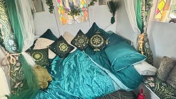Una habitación con una cama, una mesita y un ventanal con cortinas.