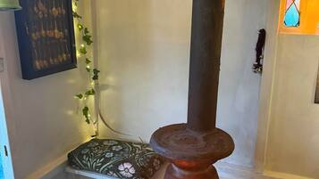 Un interior rústico con una estufa de leña, un farol que cuelga en la pared y una placa de metal decorativa.