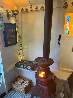 A rustic interior with a wood-burning stove, a wall-mounted lantern, and a decorative metal plate.