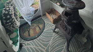 Et hyggeligt rum med en grøn dør, en hvid gardin, en fletkurv, et mønstret tæppe og en pejs.