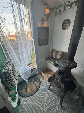 Een knus interieur met een groene deur, een wit gordijn, een rieten mand, een kamerbreed tapijt met dessin en een open haard.