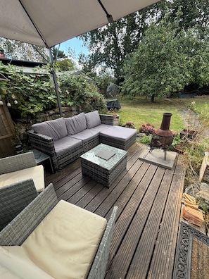 An outdoor patio with a sectional sofa, a small table, and a decorative metal sculpture.