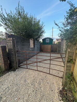 Een grindpad dat leidt naar een afgesloten gebied met een groen gebouw op de achtergrond.