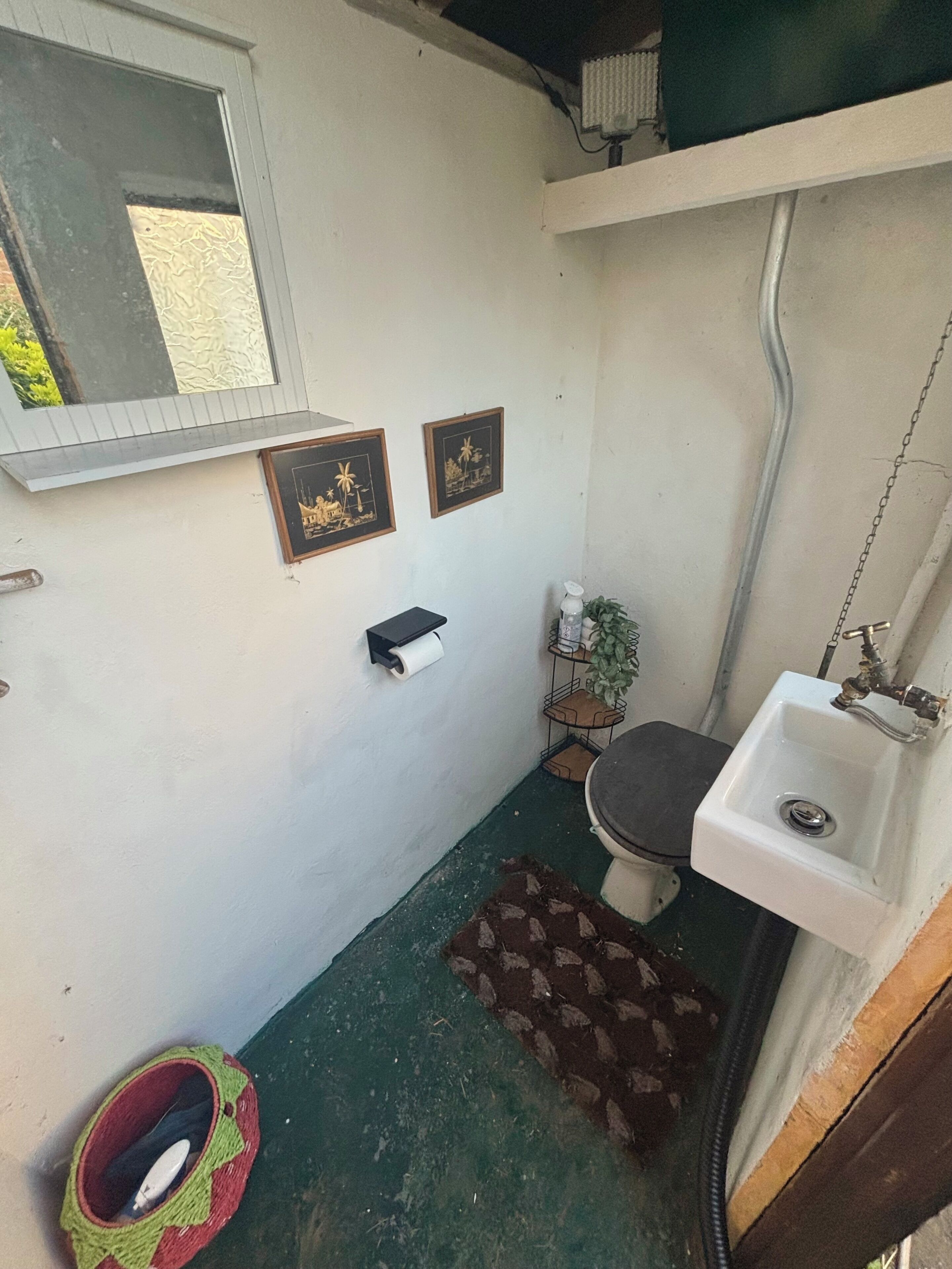 Un baño pequeño con inodoro, lavamanos y espejo.