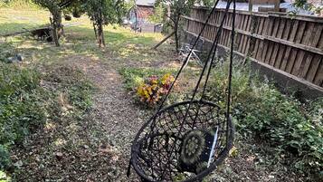 A garden with a swing set, a wooden fence, and a house in the background.