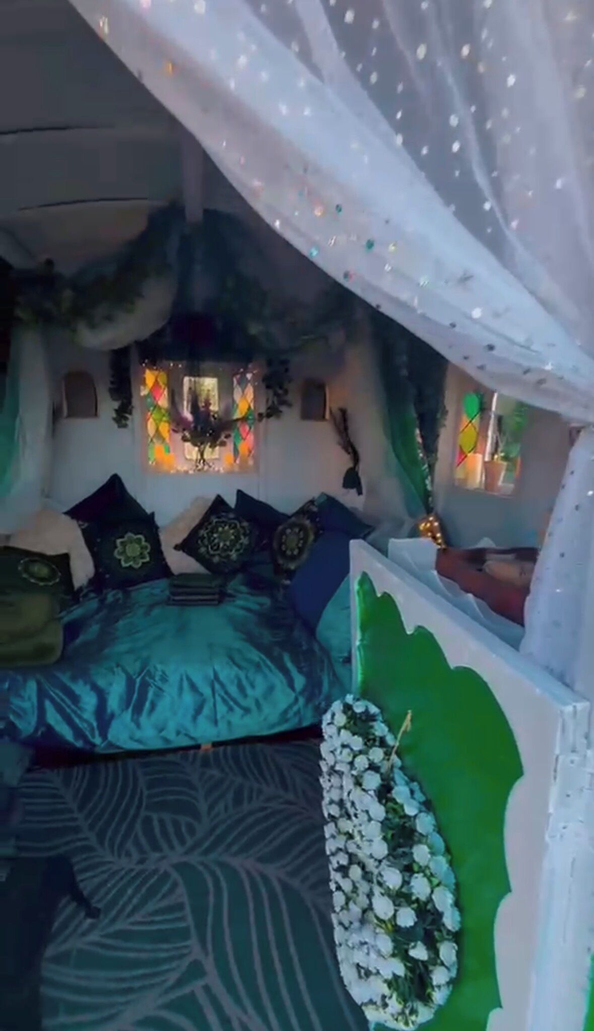 A room with a bed, a green wall, and a decorative plant.