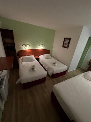 Ein Hotelzimmer mit zwei Einzelbetten, einem Holzkopfteil, einer grünen Akzentwand und einem kleinen Nachttisch mit einer Lampe.
