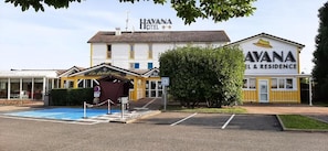 A hotel with a swimming pool, a covered outdoor seating area, and a sign for 'HAVANA HOTEL'.