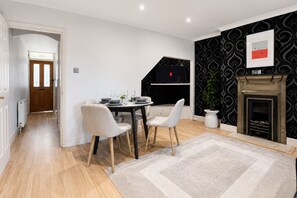 Een eethoek met een tafel gedekt voor vier personen, een open haard en een aan de muur bevestigde televisie.