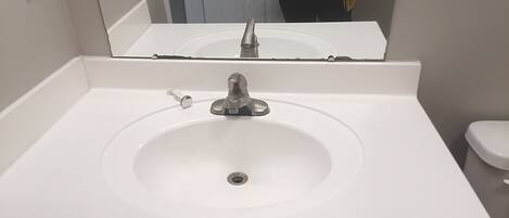 A bathroom with a white sink, a mirror above it, and a toilet to the right.