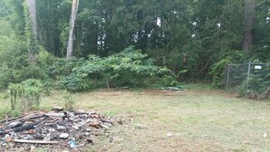 Un'area erbosa con detriti sparsi e un ammasso di materiali bruciati.