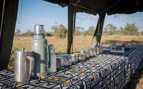 A table with various containers and a portable stove under a tent.