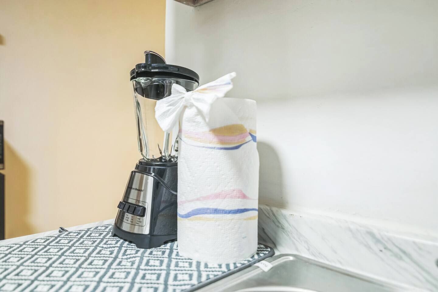 Eine Küchenarbeitsplatte mit einem Mixer und einer gestreiften Flasche.