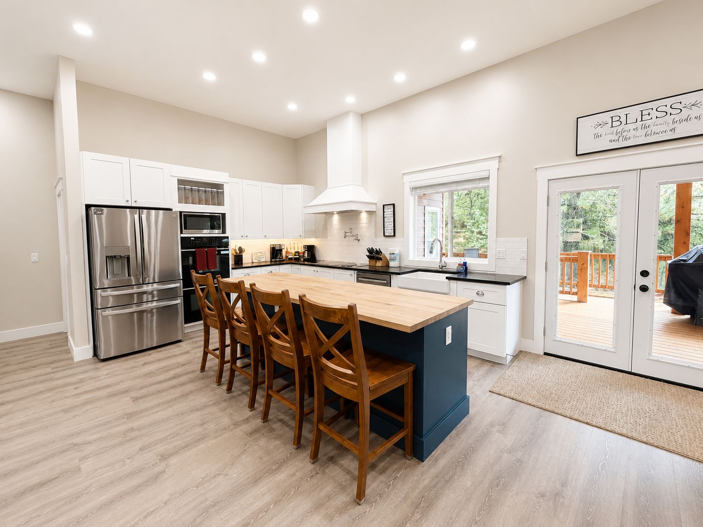 A modern kitchen with a central island, stainless steel appliances, and a view to an outdoor deck.