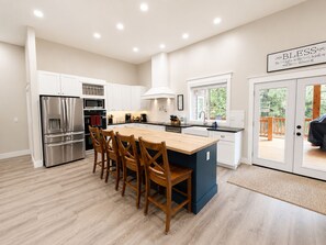 A modern kitchen with a central island, stainless steel appliances, and a view to an outdoor deck.