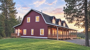 Une grande maison à deux étages, avec une façade rouge et un porche abrité.
