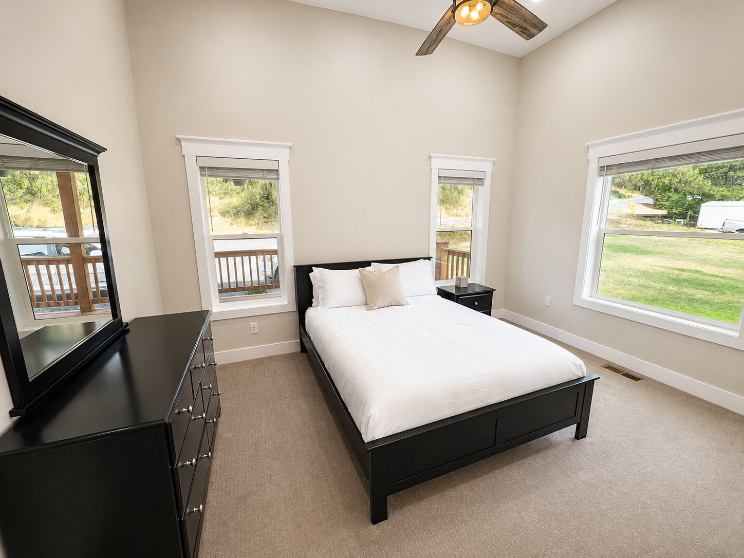 A bedroom with a bed, dresser, nightstands, and a ceiling fan.