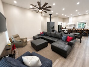 A modern living room with a sectional sofa, a recliner, a coffee table, and a ceiling fan.