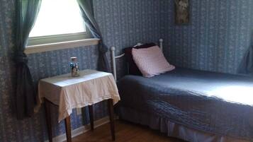 A bedroom with a single bed, a small table, and a window with curtains.