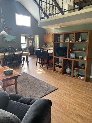 A spacious living area with a high ceiling, wooden flooring, a dining table with chairs, a sofa, a bookshelf, and a staircase. - Beautiful memories are made on the Suwannee River in Mayo Fl (Mayo)