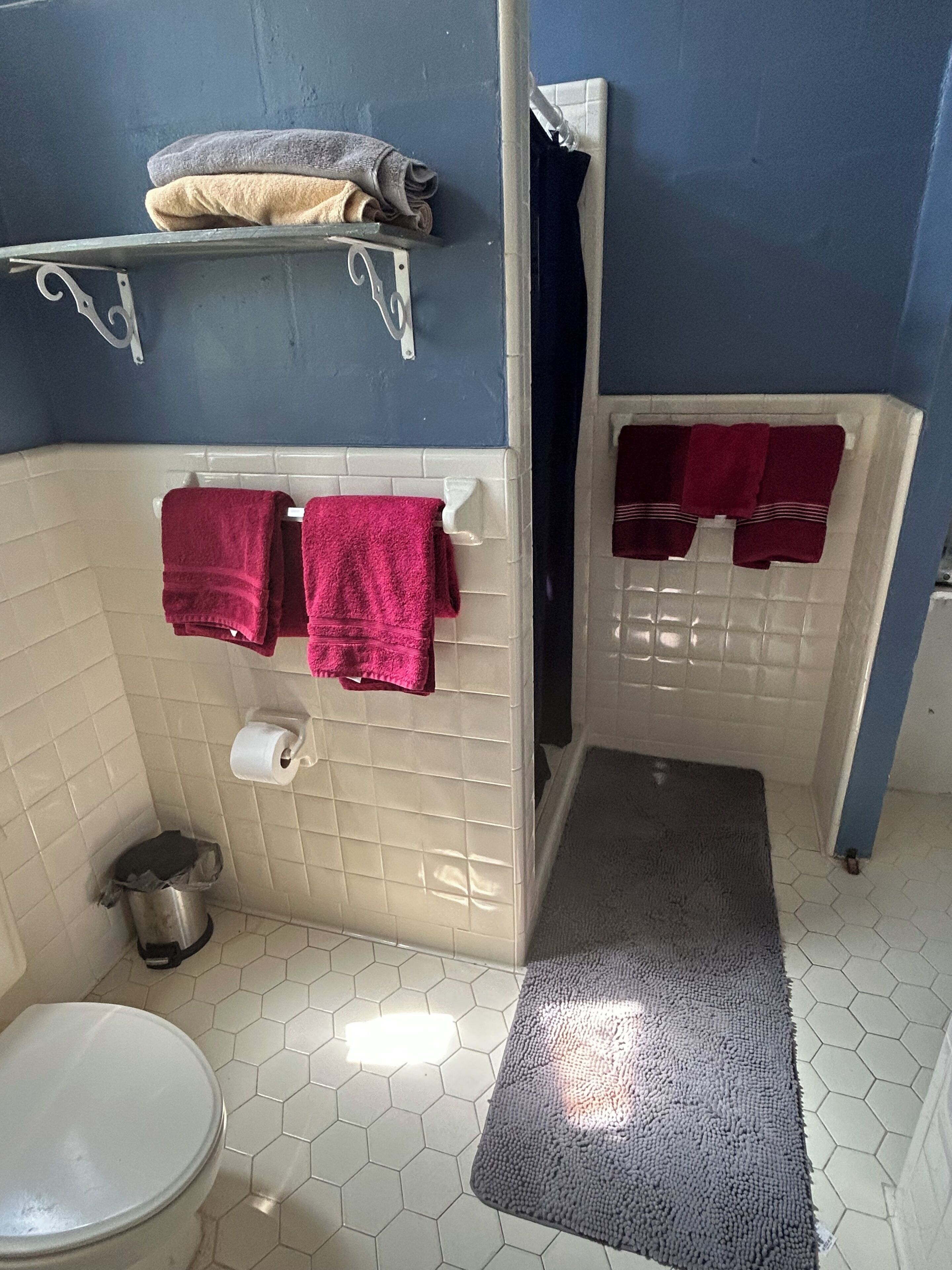 A bathroom with a toilet, a sink, a shower, and a towel rack with towels.