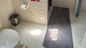 Casa de banho com sanita, lavatório, chuveiro e um porta-toalhas com toalhas.