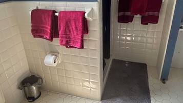 A bathroom with a toilet, a sink, a shower, and a towel rack with towels.