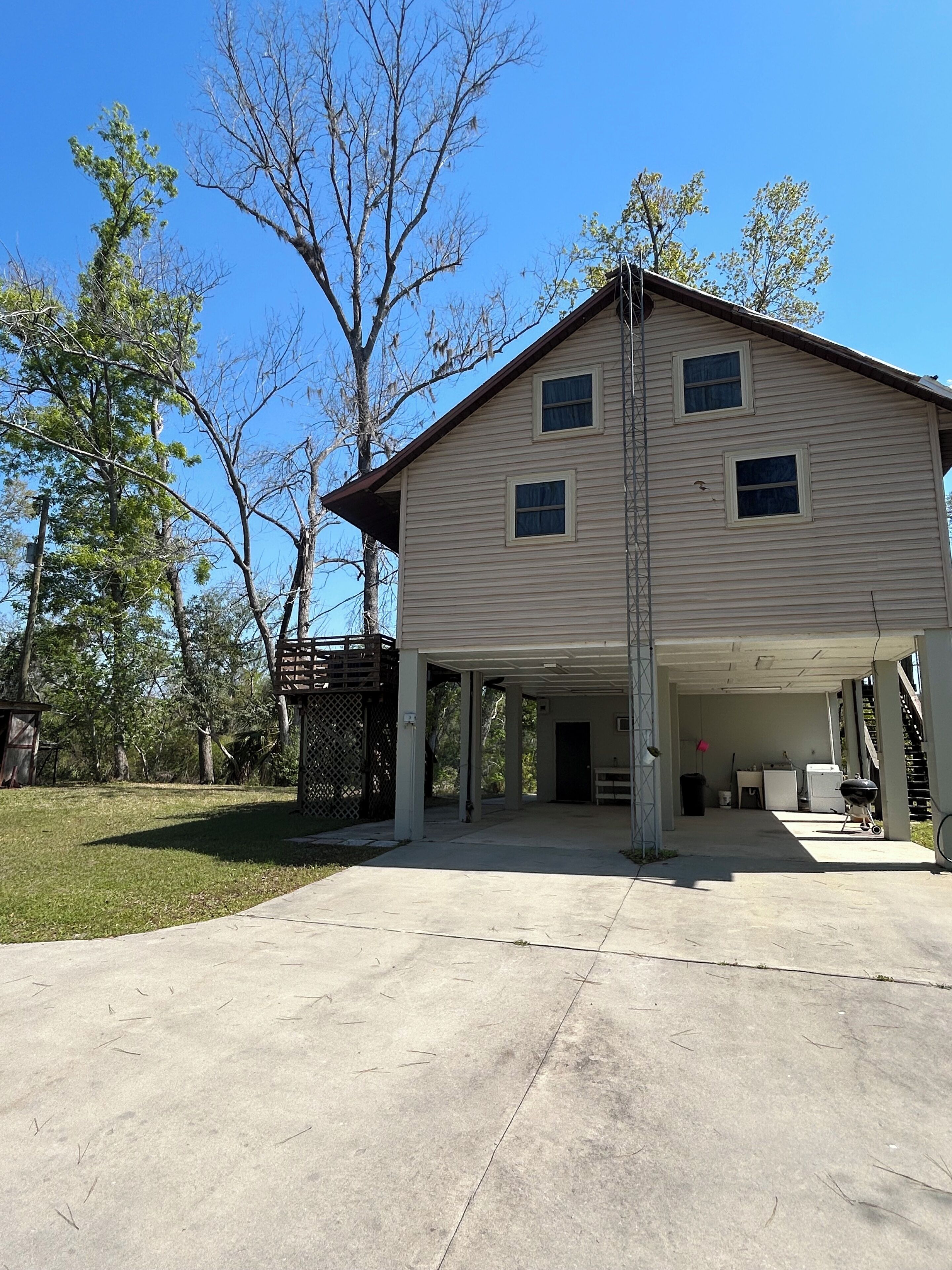 A two-story house with a covered garage, a fenced yard, and trees in the background.
