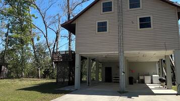 A two-story house with a covered garage, a fenced yard, and trees in the background.