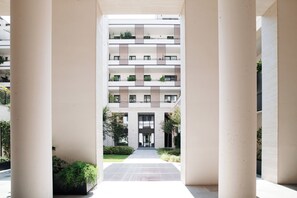 A modern multi-story residential building with a central courtyard, balconies with greenery, and a clean architectural design. - Bright 1BR near to the center of Milan (Milano)