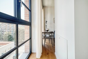A narrow corridor with a dining area featuring a table and chairs, a lamp, and a view through large windows. - Bright 1BR near to the center of Milan (Milano)