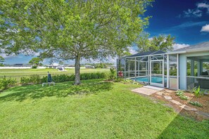 A residential property with a swimming pool, a covered outdoor area, and a well-maintained lawn. - Sunset Paradise! Heated pool, 3/2 plus office- Yes Dogs! Fenced, LUXE Upgrades! (Cape Coral)