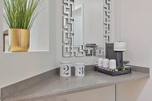 A hotel room with a coffee station, a potted plant, and a mirror with a geometric frame. - Sunset Paradise! Heated pool, 3/2 plus office- Yes Dogs! Fenced, LUXE Upgrades! (Cape Coral)