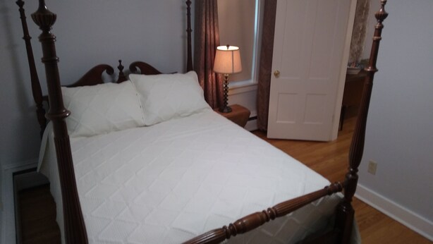 A bedroom with a four-poster bed, a bedside table with a lamp, and a door leading to another room. - Apartment for the traveling professional (Bristol)