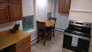 A kitchen with wooden cabinets, a dining table with chairs, and a built-in oven. - Apartment for the traveling professional (Bristol)