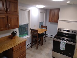 A kitchen with wooden cabinets, a dining table with chairs, and a built-in oven. - Apartment for the traveling professional (Bristol)