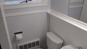 A bathroom with a toilet, sink, radiator, and a window with a blind. - Apartment for the traveling professional (Bristol)