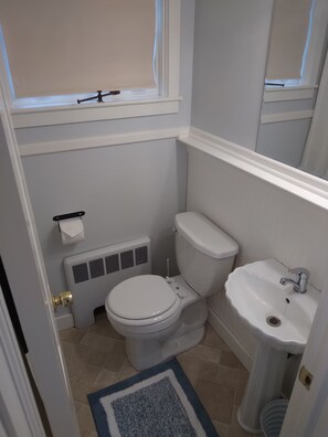 A bathroom with a toilet, sink, radiator, and a window with a blind. - Apartment for the traveling professional (Bristol)