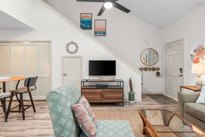 Ein Wohnzimmer mit Fernseher, Sofa und Essbereich.