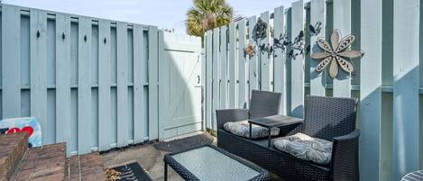 A patio area with a wicker sofa, a small table, and a decorative butterfly wall piece.