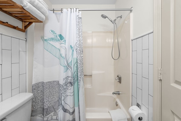 Een badkamer met een douche, toilet en bad.