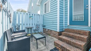 Ein blaues Haus mit Veranda, Sitzgelegenheiten im Freien und einer Ziegelsteintreppe.