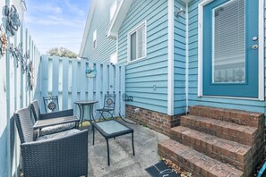 Ein blaues Haus mit Veranda, Sitzgelegenheiten im Freien und einer Ziegelsteintreppe.