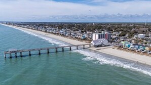 Eine Küstenstadt mit einem Steg, der ins Meer führt, Immobilien direkt am Strand und freiem Blick auf den Ozean.