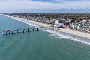 Eine Küstenstadt mit einem Steg, der ins Meer führt, Immobilien direkt am Strand und freiem Blick auf den Ozean.