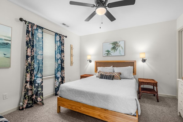 A bedroom with a bed, two bedside tables, a ceiling fan, and a nightstand with a lamp. - Castaway Beach Bungalow Pets Welcome (Surfside Beach)