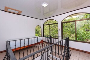 Une pièce dotée d’un balcon, de grandes fenêtres en arc de cercle et d’un banc en bois.